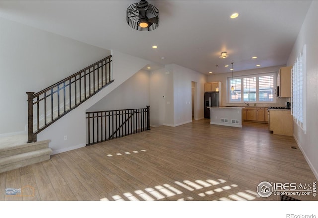 unfurnished living room featuring ceiling fan and light hardwood / wood-style floors