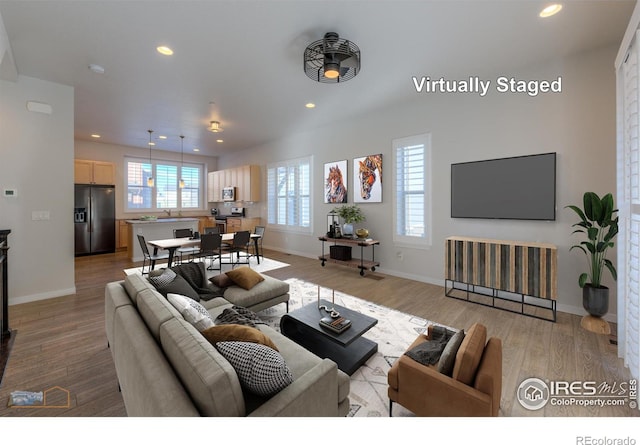 living room featuring light wood-type flooring and ceiling fan