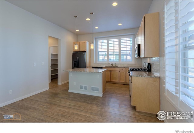 kitchen featuring a center island, black fridge, sink, range with gas stovetop, and light hardwood / wood-style floors