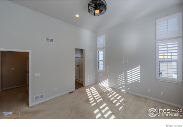 unfurnished room with light colored carpet and high vaulted ceiling