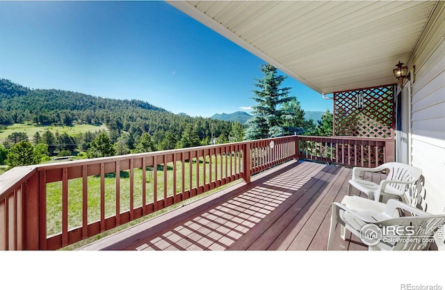 wooden deck featuring a lawn and a mountain view