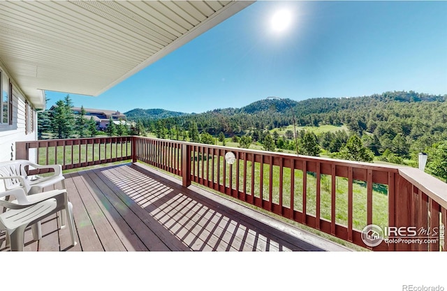 wooden deck with a mountain view and a yard