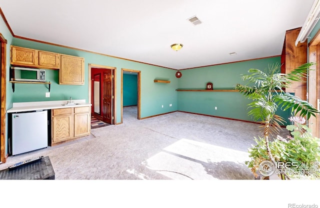 kitchen featuring white refrigerator, light colored carpet, crown molding, and sink