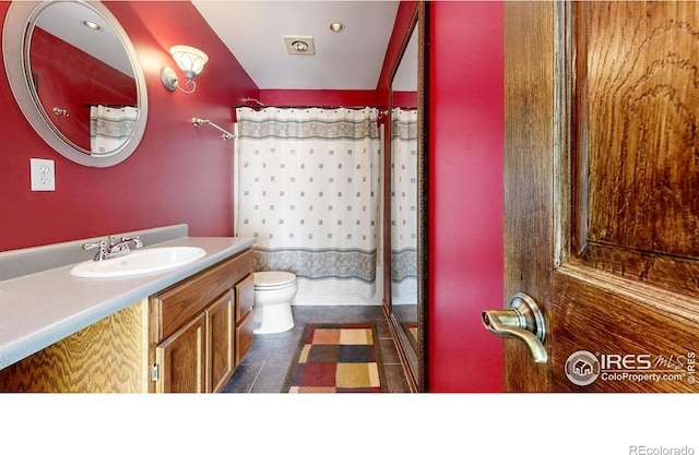 bathroom with tile patterned flooring, vanity, toilet, and walk in shower