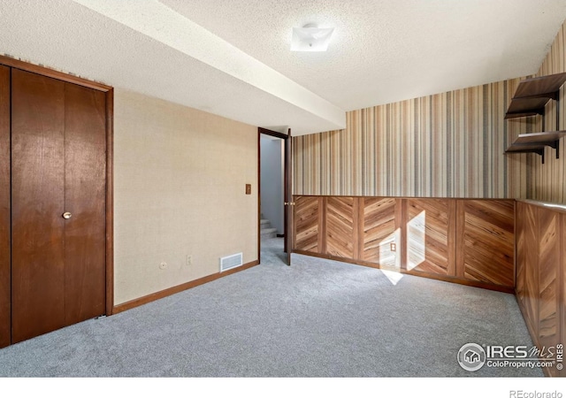 basement featuring a textured ceiling and carpet floors