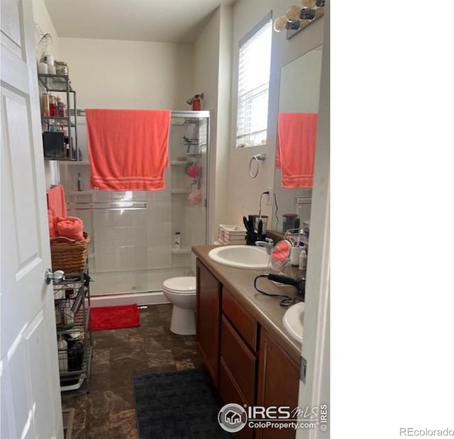 bathroom featuring vanity, a shower with shower door, and toilet