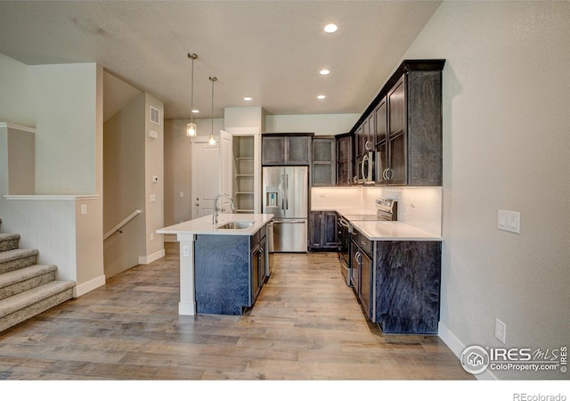 kitchen with dark brown cabinetry, sink, decorative light fixtures, a center island with sink, and appliances with stainless steel finishes