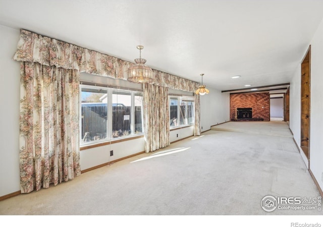 unfurnished living room featuring carpet flooring, a wood stove, and a notable chandelier