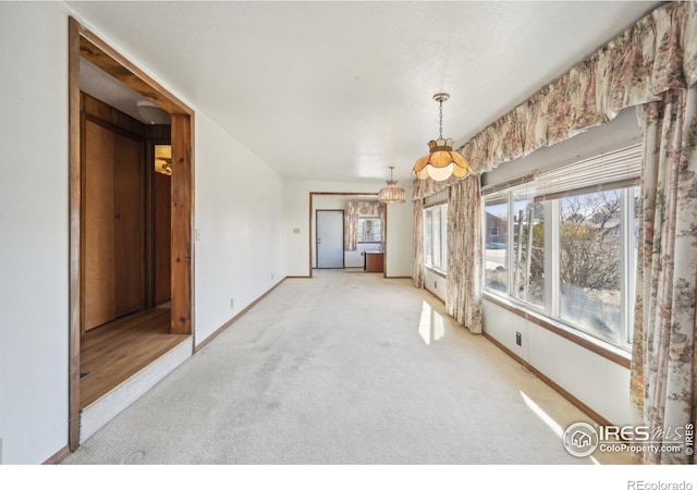 empty room featuring light colored carpet and a chandelier