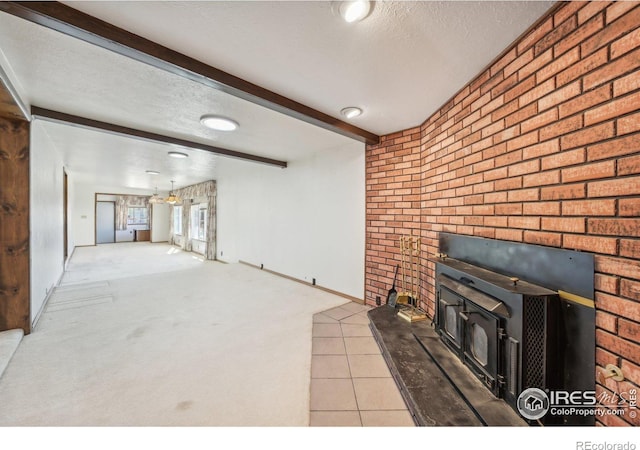 unfurnished living room with a wood stove, light carpet, beamed ceiling, and a textured ceiling