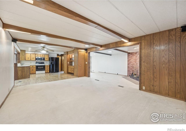 unfurnished living room featuring wood walls, ceiling fan, beam ceiling, and light carpet