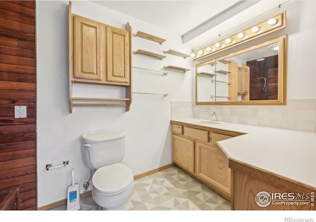 bathroom featuring vanity, toilet, and tasteful backsplash