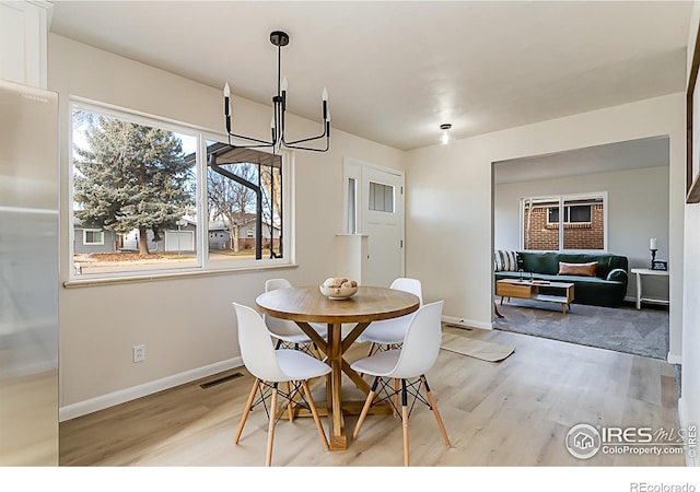 dining room featuring light wood-style floors, visible vents, baseboards, and a chandelier