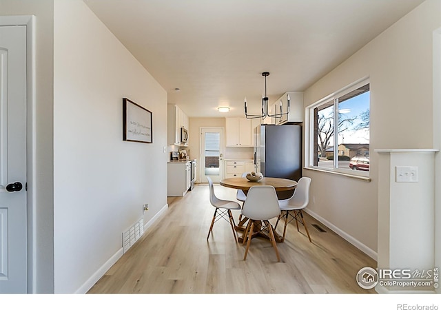 dining room featuring baseboards, visible vents, and light wood-style floors