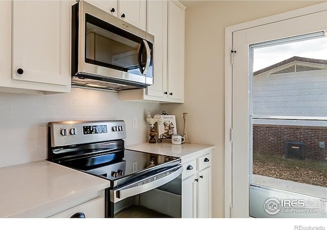 kitchen featuring tasteful backsplash, white cabinetry, stainless steel appliances, and light countertops