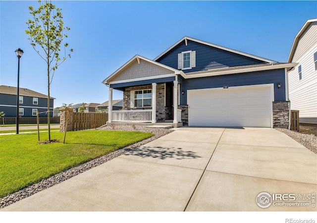 view of front of house with covered porch, a garage, and a front lawn