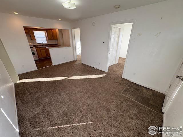 unfurnished living room with dark carpet and sink