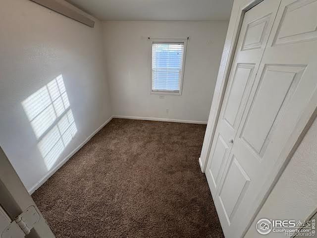 unfurnished bedroom featuring a closet and dark carpet
