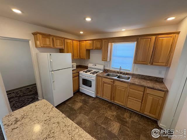 kitchen with light stone counters, sink, and white appliances