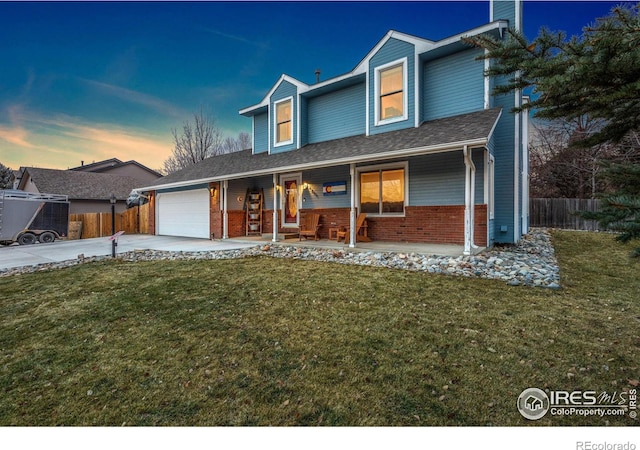 view of front of house featuring covered porch, a garage, and a yard