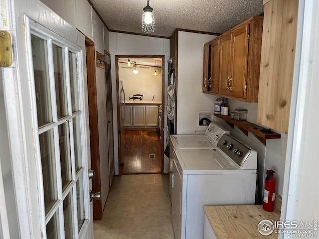 laundry room featuring ceiling fan, cabinets, washing machine and dryer, a textured ceiling, and ornamental molding