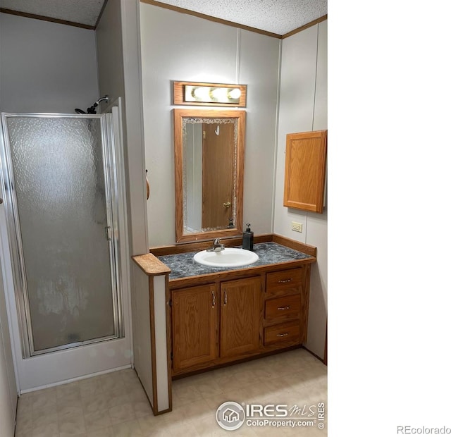 bathroom featuring vanity, a shower with shower door, and a textured ceiling