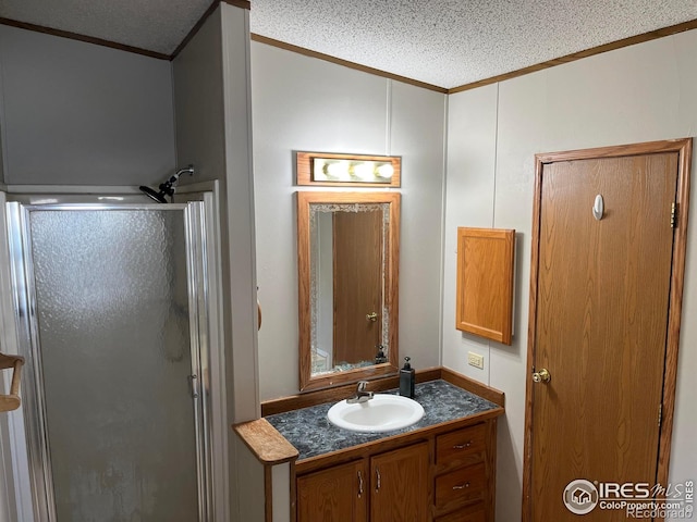 bathroom with crown molding, vanity, a textured ceiling, and walk in shower