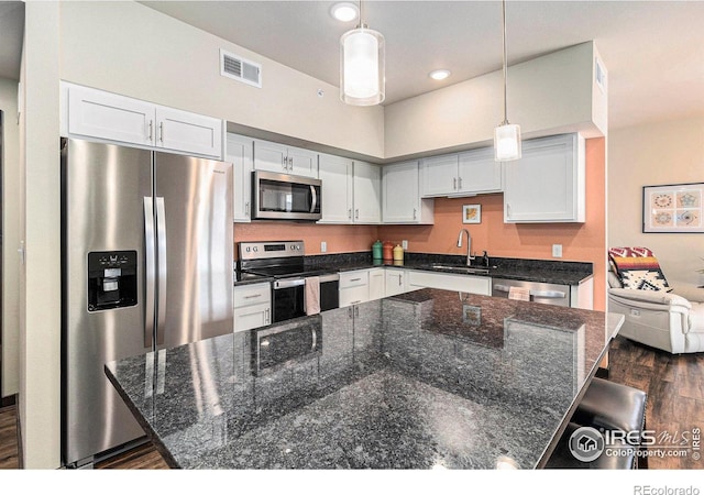 kitchen with white cabinetry, sink, dark wood-type flooring, decorative light fixtures, and appliances with stainless steel finishes