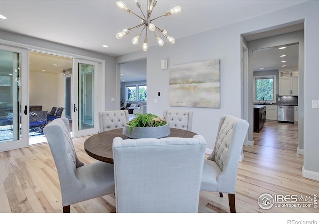 dining room featuring plenty of natural light, a notable chandelier, and light wood-type flooring