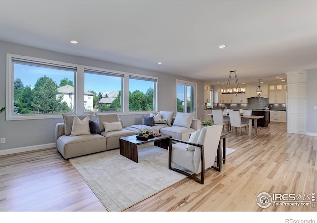 living room with light wood-type flooring and a chandelier