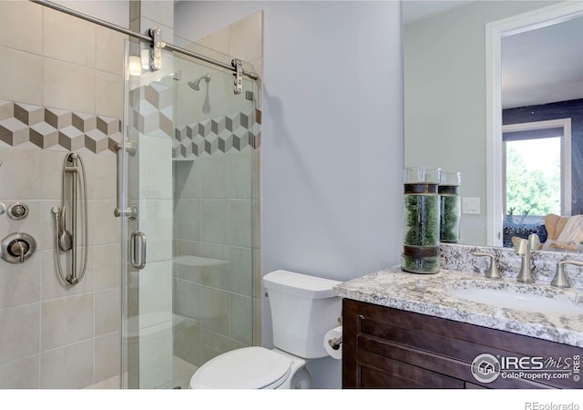 bathroom featuring vanity, toilet, and a shower with shower door