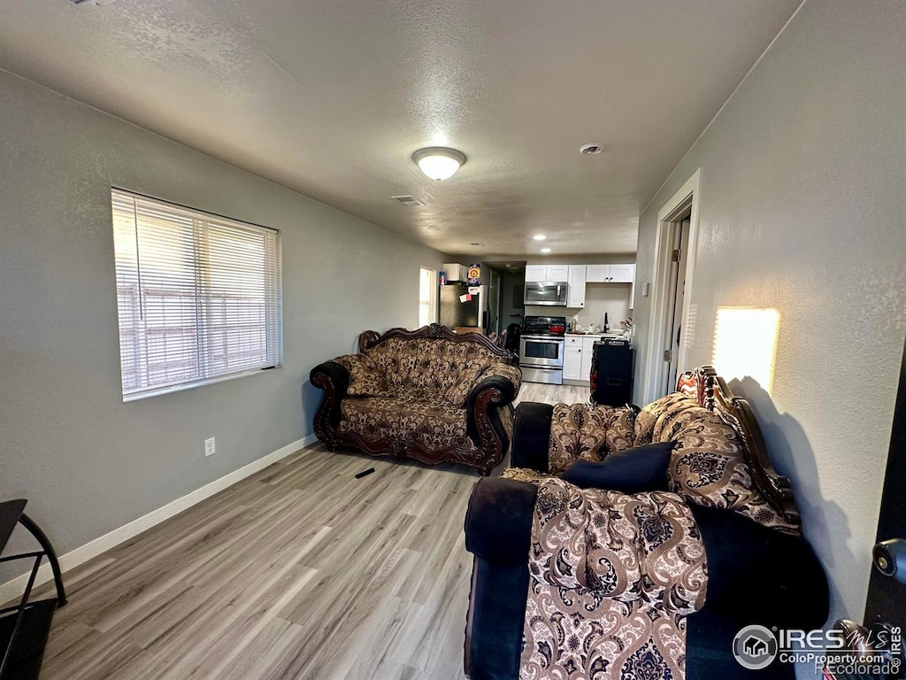 living room featuring light wood-type flooring and a textured ceiling