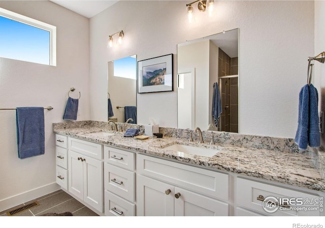 bathroom with tile patterned floors, vanity, and a tile shower