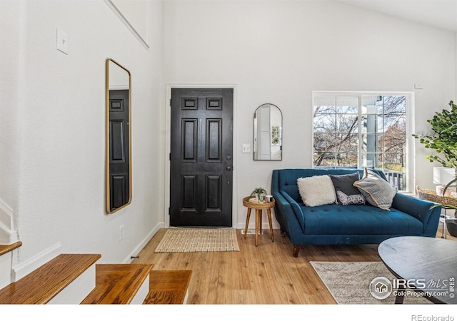 foyer with high vaulted ceiling, light wood-style flooring, and baseboards