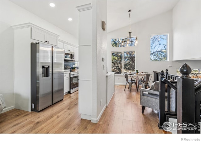 kitchen featuring stainless steel appliances, backsplash, light wood-style flooring, white cabinetry, and high vaulted ceiling