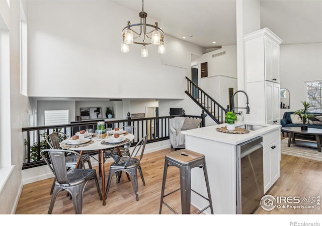 kitchen with high vaulted ceiling, white cabinets, a sink, and an inviting chandelier