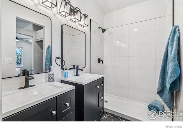 bathroom featuring two vanities, tiled shower, a sink, and a ceiling fan