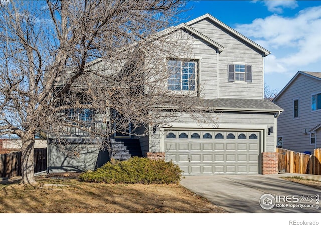 view of front of house featuring driveway, a garage, fence, and brick siding