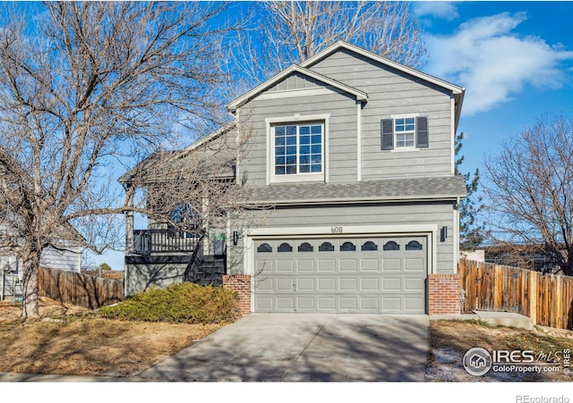 traditional-style house with brick siding, concrete driveway, fence, a garage, and stairs