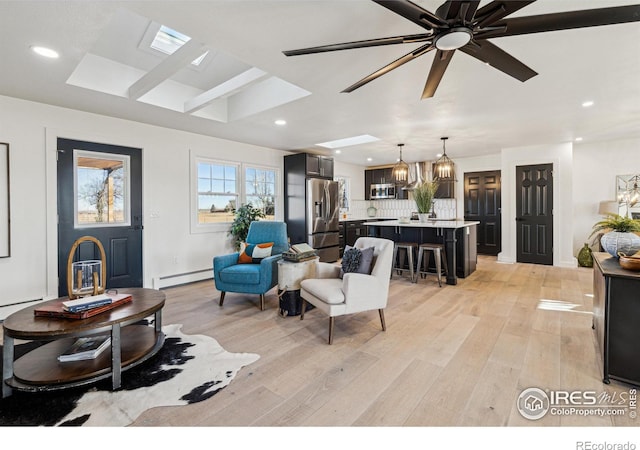 living room with ceiling fan with notable chandelier, light hardwood / wood-style floors, and baseboard heating