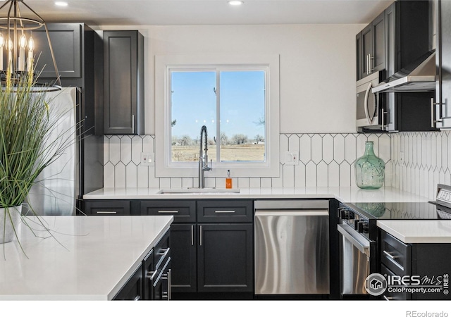 kitchen with sink, hanging light fixtures, an inviting chandelier, range hood, and appliances with stainless steel finishes