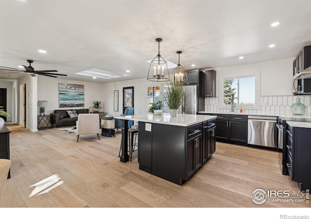 kitchen with tasteful backsplash, stainless steel appliances, a center island, hanging light fixtures, and a breakfast bar area