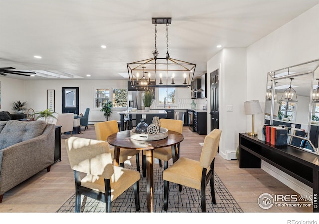 dining area featuring ceiling fan, sink, light wood-type flooring, and baseboard heating