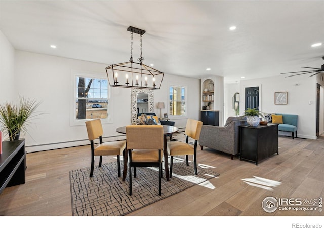 dining room with ceiling fan with notable chandelier, a baseboard radiator, and light hardwood / wood-style flooring