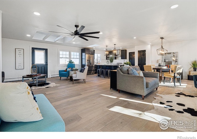 living room featuring baseboard heating, ceiling fan, and light wood-type flooring