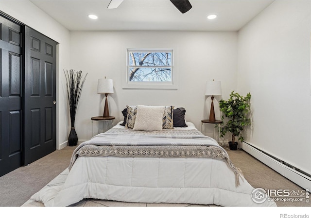 bedroom with a closet, light colored carpet, ceiling fan, and a baseboard heating unit