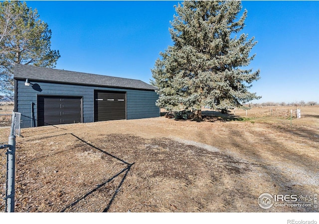 garage featuring fence and dirt driveway