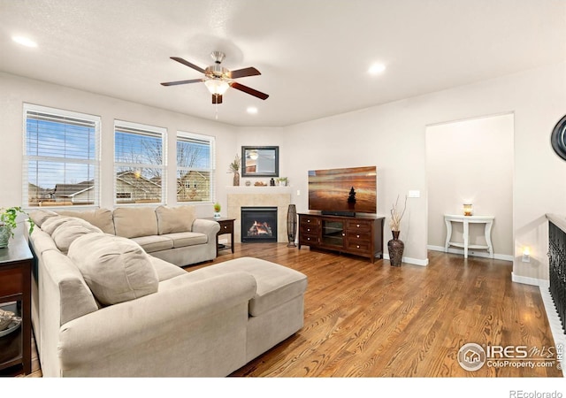 living room with hardwood / wood-style flooring, ceiling fan, and a tile fireplace