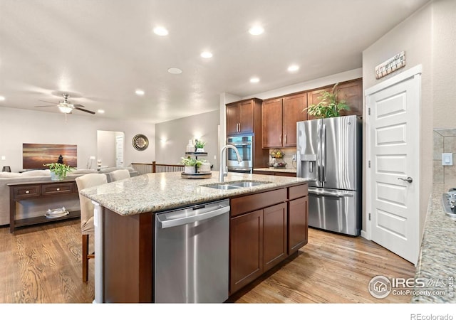 kitchen featuring sink, light wood-type flooring, an island with sink, and appliances with stainless steel finishes