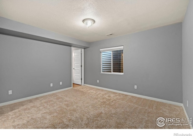 empty room with light carpet and a textured ceiling